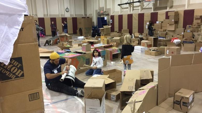 Photo of gymnasium filled with cardboard boxes and children playing 
